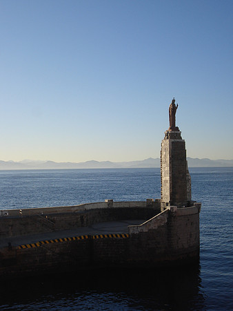 A statue of Jesus at the entrance of the port of Tarifa with a view of Morocco in the background,Tarifa - Spain.